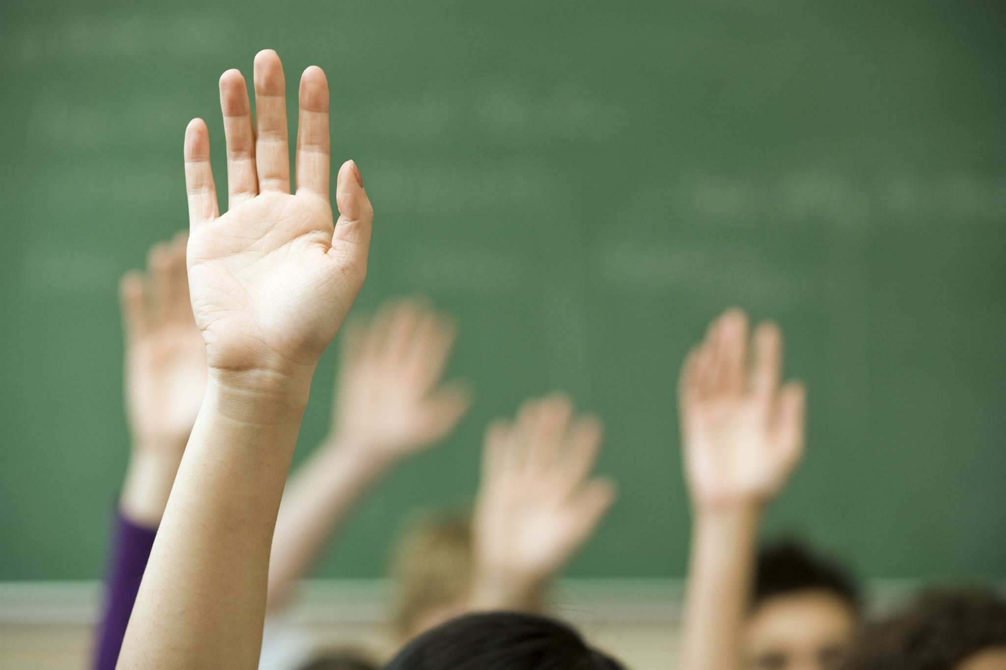 Close-up-of-hands-raised-in-classroom